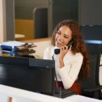 Front desk worker smiling while talking on the phone in a medical spa