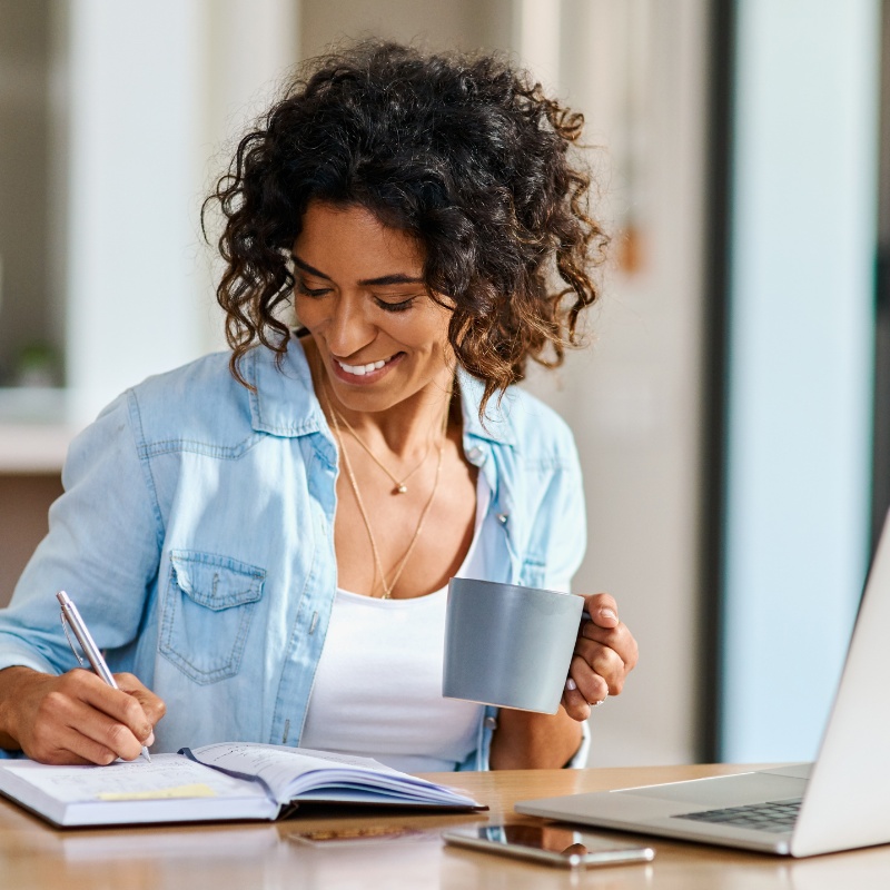 a woman looking at their computer or writing something down