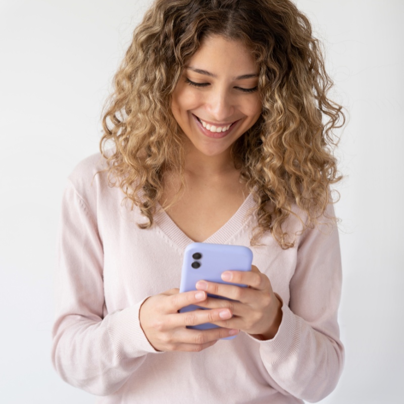a woman looking at their phone and looking happy