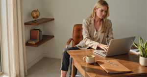 Woman working on a laptop in a warm, modern office.