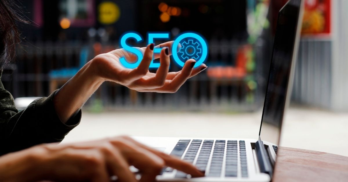 Person using a laptop with a glowing SEO icon, representing search engine optimization and digital marketing.
